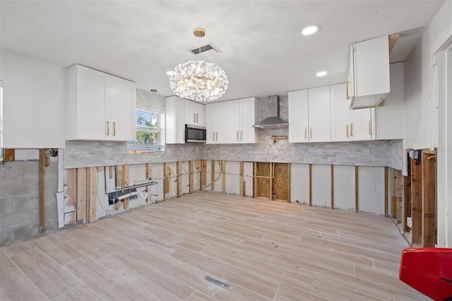 kitchen featuring tasteful backsplash, decorative light fixtures, white cabinets, and wall chimney exhaust hood