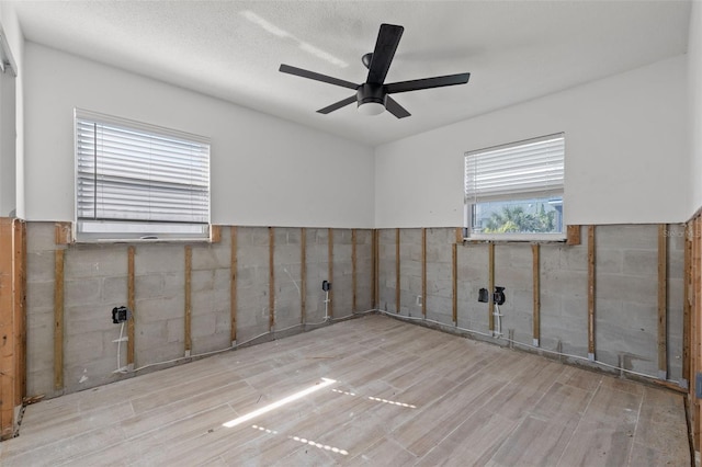 empty room with ceiling fan, light hardwood / wood-style flooring, and a textured ceiling