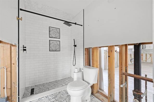 bathroom with a tile shower and toilet