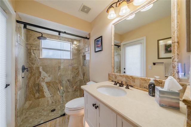 bathroom featuring vanity, a shower with shower door, and toilet