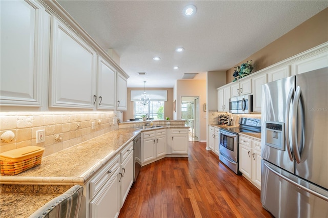 kitchen with sink, white cabinetry, hanging light fixtures, stainless steel appliances, and dark hardwood / wood-style flooring