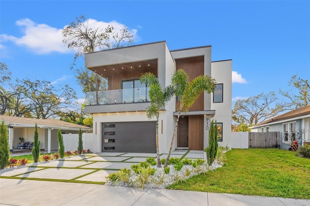 modern home featuring a garage, a balcony, and a front yard