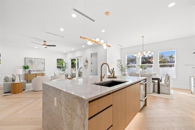 kitchen featuring a large island, sink, light stone countertops, and light parquet floors