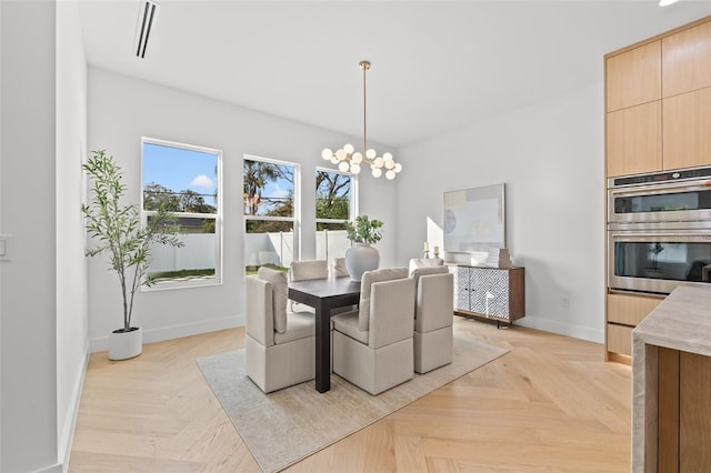 dining area with a notable chandelier and light parquet flooring