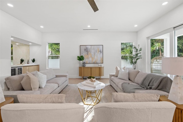 living room with indoor bar, beverage cooler, and light hardwood / wood-style flooring