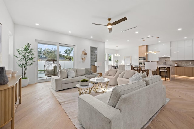 living room with light parquet flooring and ceiling fan with notable chandelier