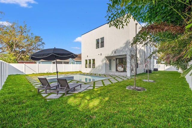 rear view of house with a patio, a fenced in pool, and a lawn