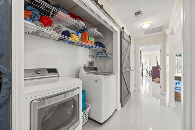 1007 Lake Avoca Dr, Tarpon Springs, FL 34689 - washroom featuring light tile patterned flooring, independent washer and dryer, and a barn door