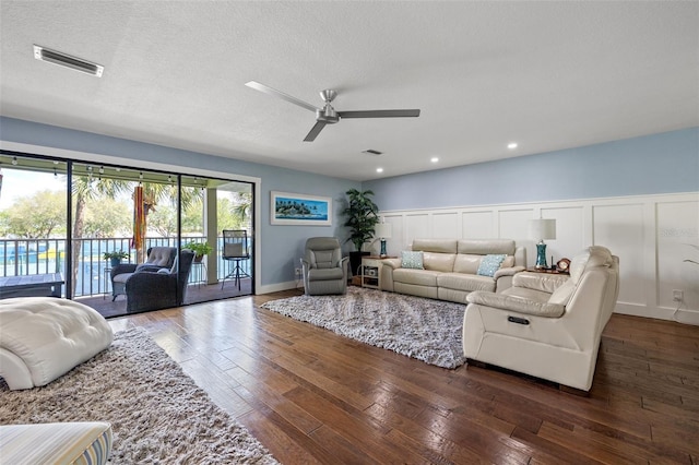 living room with ceiling fan, dark hardwood / wood-style floors, and a textured ceiling