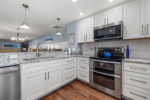 kitchen featuring dark wood-type flooring, sink, white cabinetry, hanging light fixtures, and appliances with stainless steel finishes