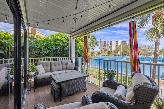 wooden deck with a water view and outdoor lounge area