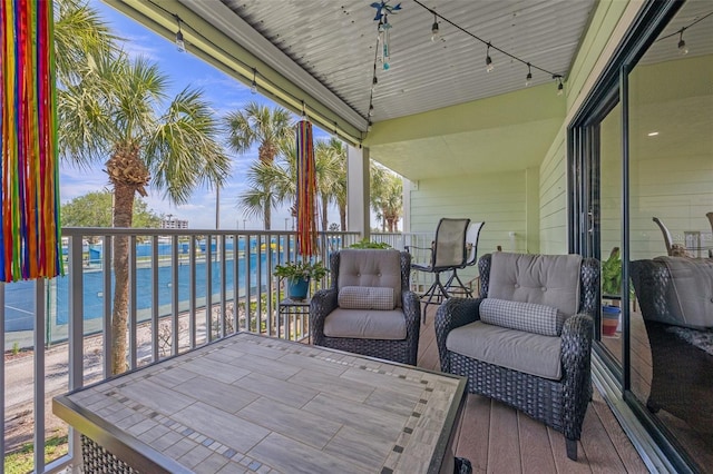 sunroom with rail lighting, a water view, and a wealth of natural light