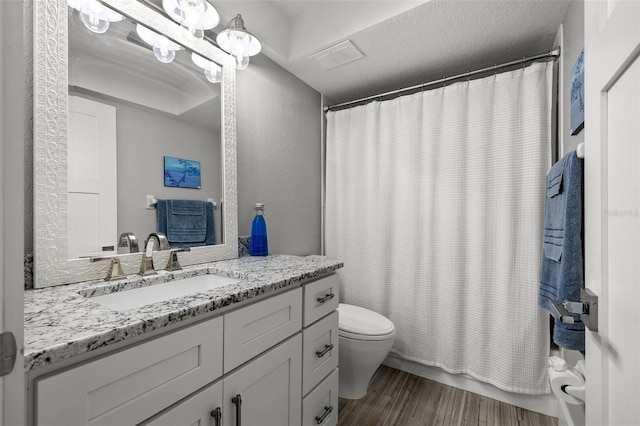 bathroom featuring vanity, hardwood / wood-style floors, a textured ceiling, and toilet