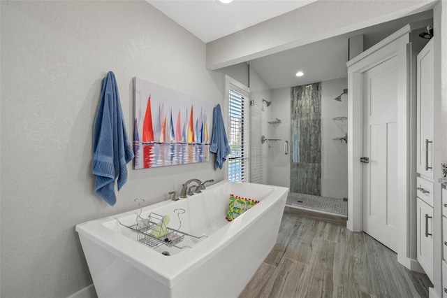 bathroom with wood-type flooring and shower with separate bathtub