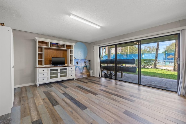 unfurnished living room with hardwood / wood-style flooring, plenty of natural light, and a textured ceiling