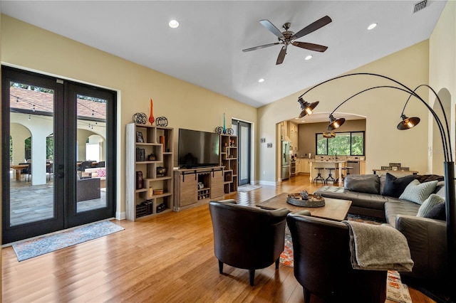 living room with light hardwood / wood-style flooring, french doors, ceiling fan, and vaulted ceiling