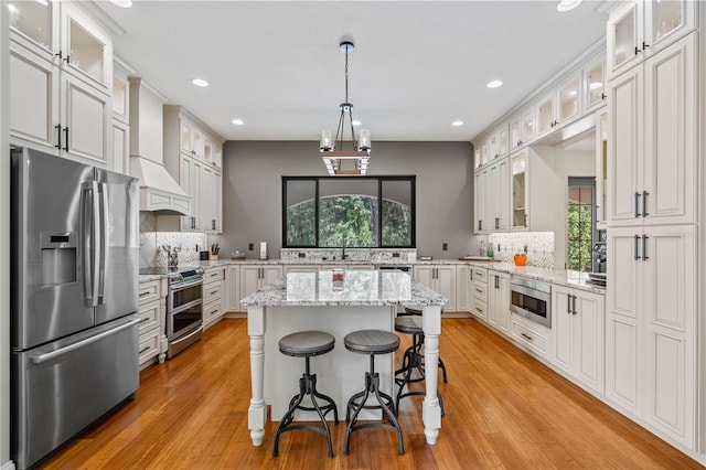 kitchen featuring white cabinetry, stainless steel appliances, custom exhaust hood, and a kitchen island