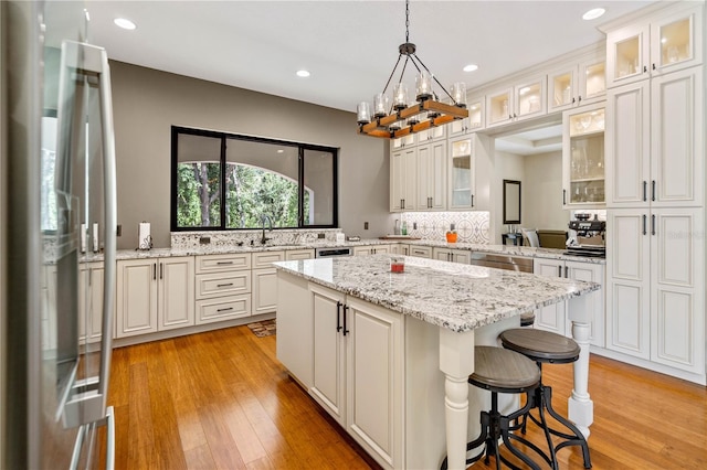 kitchen with a kitchen island, pendant lighting, white cabinets, and refrigerator