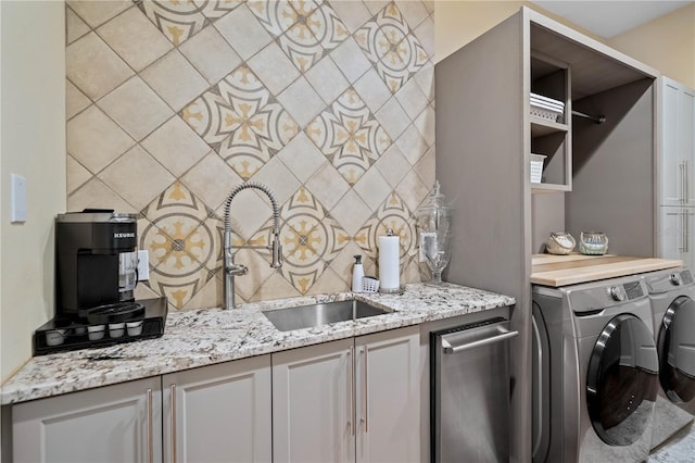 clothes washing area featuring sink, cabinets, and washer and dryer