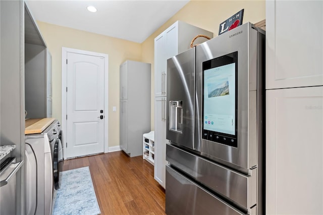 kitchen featuring white cabinetry, washer / clothes dryer, stainless steel fridge, and light hardwood / wood-style floors