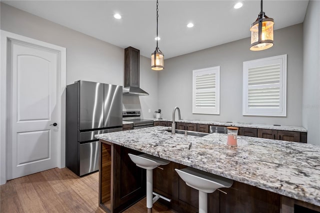 kitchen with dark brown cabinetry, sink, light stone counters, decorative light fixtures, and appliances with stainless steel finishes