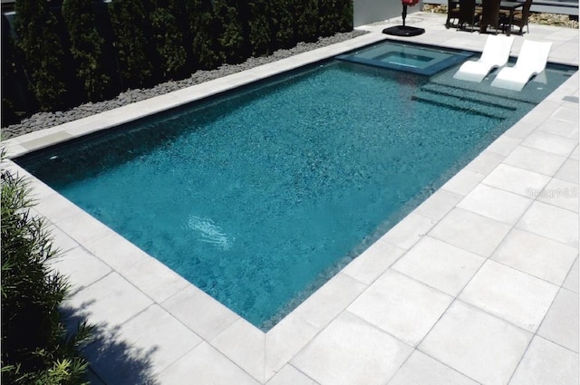 view of pool featuring a patio area and an in ground hot tub