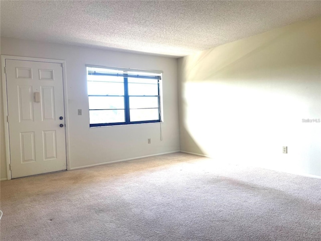 spare room with light colored carpet and a textured ceiling