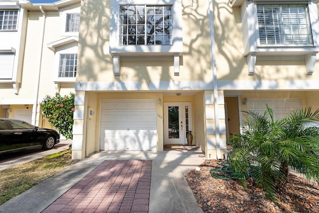 view of exterior entry featuring decorative driveway, an attached garage, and stucco siding