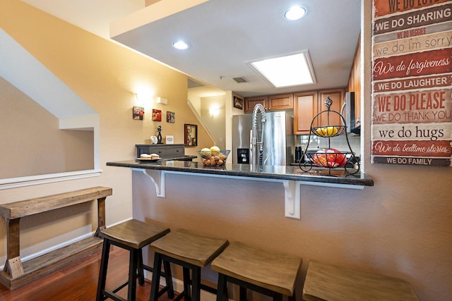 102 Brent Cir, Oldsmar, FL 34677 - kitchen featuring appliances with stainless steel finishes, a breakfast bar, brown cabinets, dark countertops, and recessed lighting