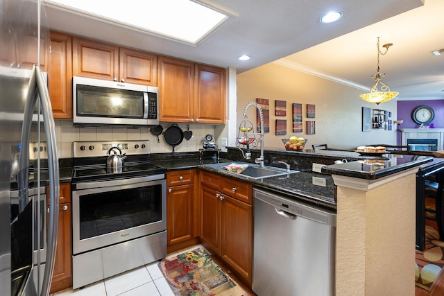 102 Brent Cir, Oldsmar, FL 34677 - kitchen featuring stainless steel appliances, a peninsula, a sink, crown molding, and brown cabinetry
