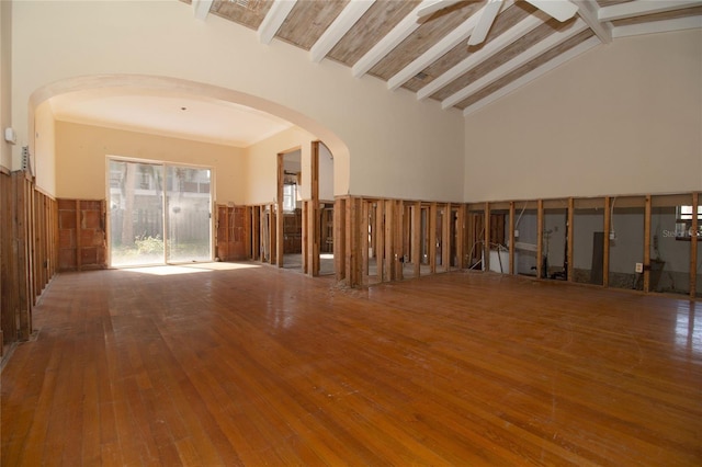 empty room with hardwood / wood-style floors, high vaulted ceiling, beamed ceiling, and ceiling fan