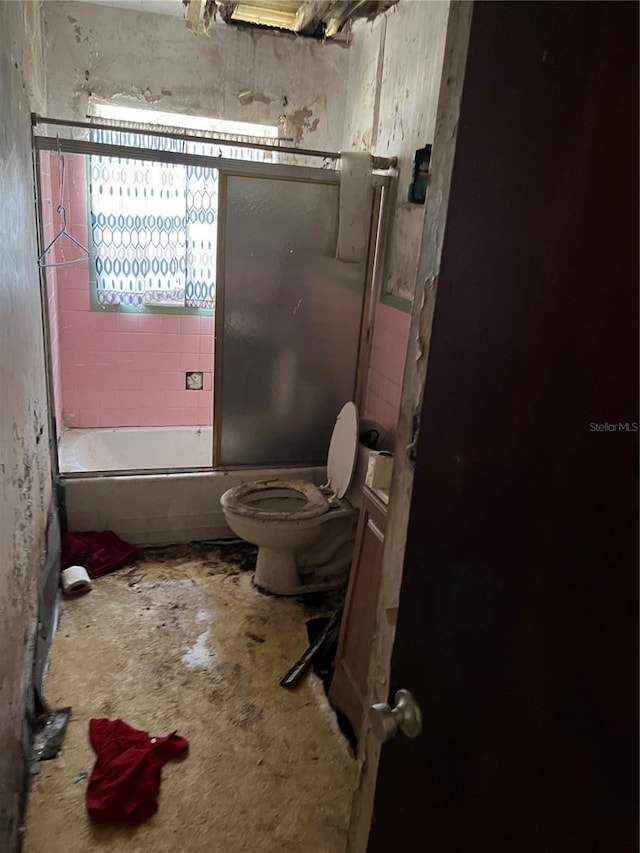 bathroom with tiled shower / bath, concrete floors, and toilet