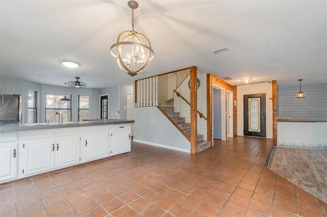 kitchen featuring sink, white cabinetry, light tile patterned floors, a notable chandelier, and pendant lighting