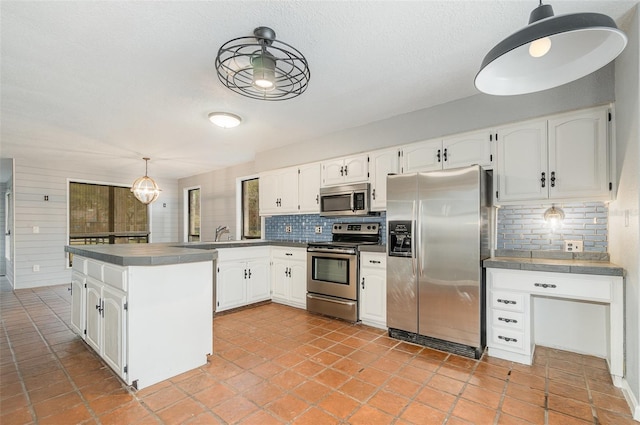 kitchen featuring backsplash, decorative light fixtures, stainless steel appliances, and white cabinets