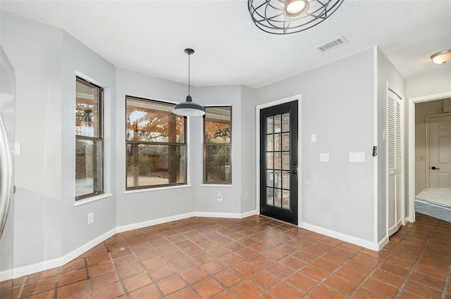 unfurnished dining area featuring dark tile patterned flooring and a textured ceiling