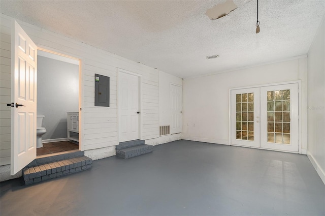 interior space with french doors, electric panel, and a textured ceiling