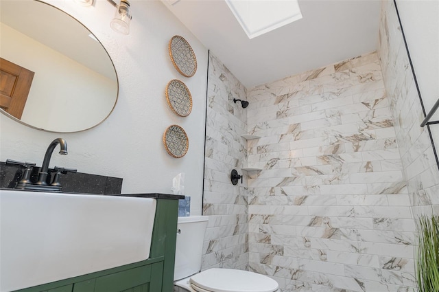 bathroom with vanity, toilet, and tiled shower