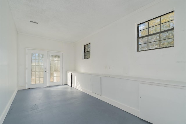 empty room featuring concrete flooring, french doors, and a textured ceiling