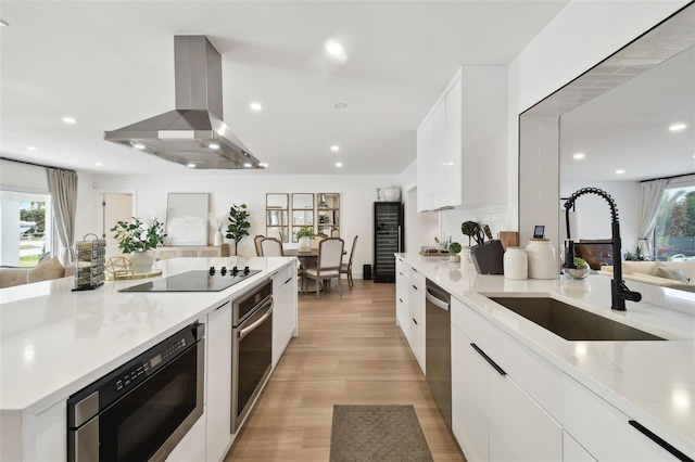 kitchen with white cabinets, island exhaust hood, sink, and black appliances