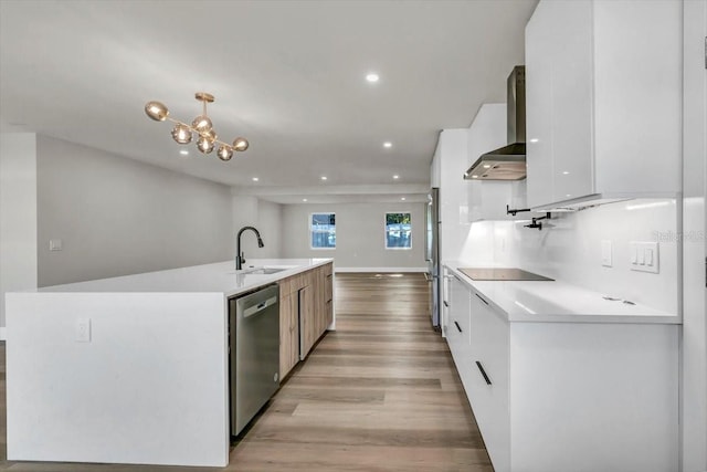 kitchen featuring wall chimney exhaust hood, white cabinetry, light wood-type flooring, appliances with stainless steel finishes, and pendant lighting