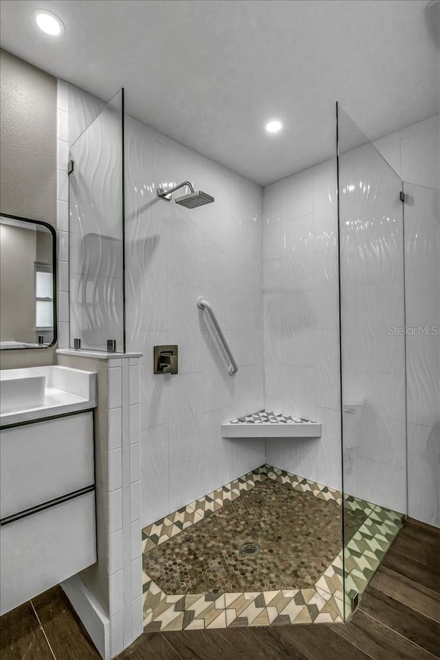 bathroom featuring hardwood / wood-style floors, vanity, and a tile shower