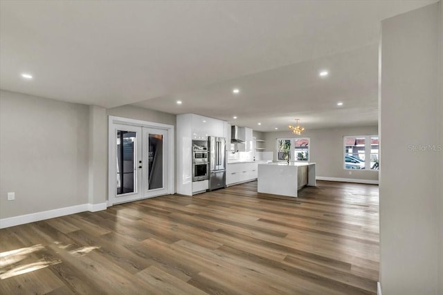 kitchen featuring pendant lighting, white cabinets, a kitchen island, french doors, and wall chimney exhaust hood