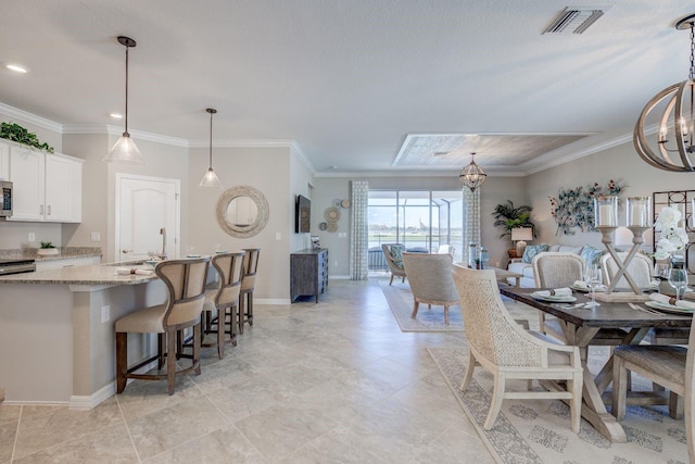 dining area featuring an inviting chandelier, sink, and ornamental molding