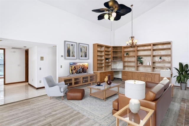 living room featuring light wood-type flooring, ceiling fan with notable chandelier, and high vaulted ceiling