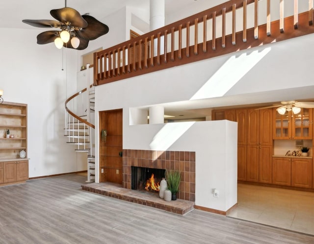 unfurnished living room with ceiling fan, light hardwood / wood-style flooring, and a high ceiling