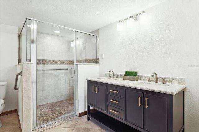 bathroom featuring a shower with door, vanity, a textured ceiling, tile patterned floors, and toilet