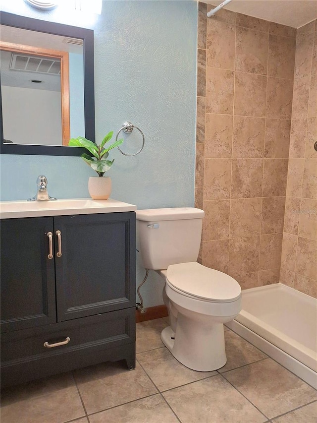 bathroom with tile patterned floors, vanity, toilet, and a tile shower