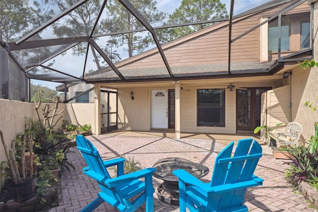 exterior space featuring a fire pit, ceiling fan, and glass enclosure