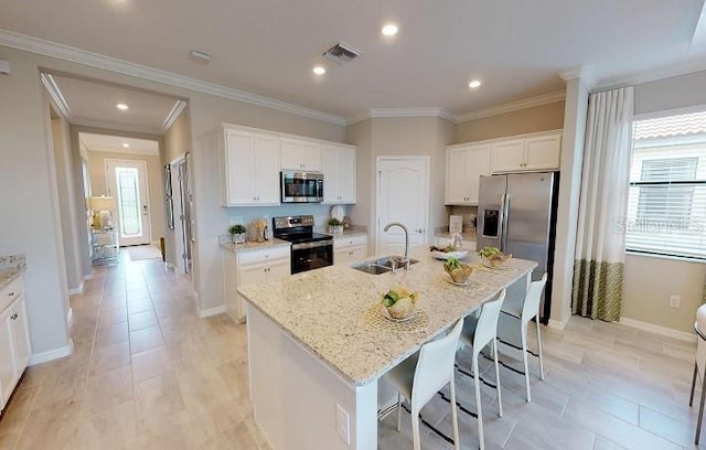 kitchen featuring sink, stainless steel appliances, light stone countertops, white cabinets, and a center island with sink