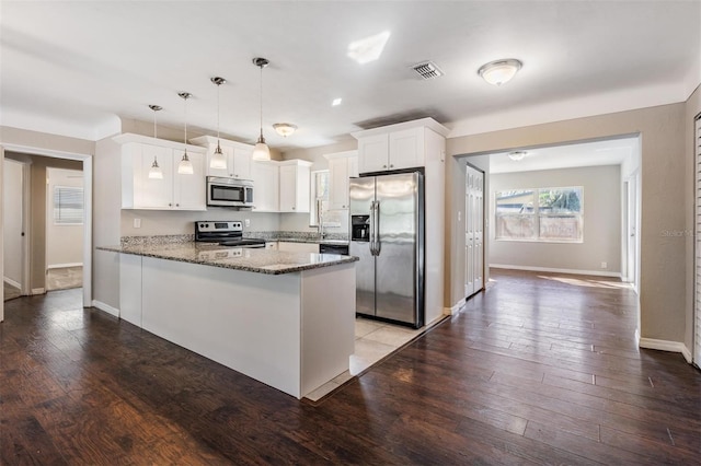 kitchen featuring pendant lighting, white cabinets, dark stone counters, kitchen peninsula, and stainless steel appliances